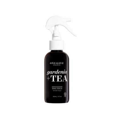 A 120ml spray bottle of One+Love Botanicals Gardenia + Tea Antioxidant Body Serum, featuring a dark brown bottle and a white trigger spray nozzle, set against a plain white background.